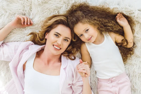 Top view of happy mom and daughter lying on sheep skin blanket and looking at camera — Stock Photo
