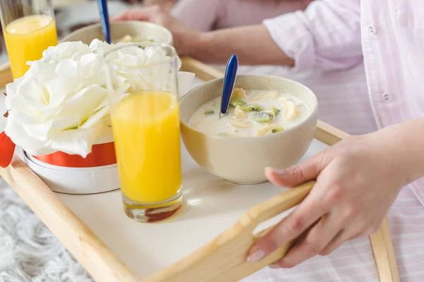 Cropped view of woman holding tray with yogurt and orange juice for breakfast — Stock Photo