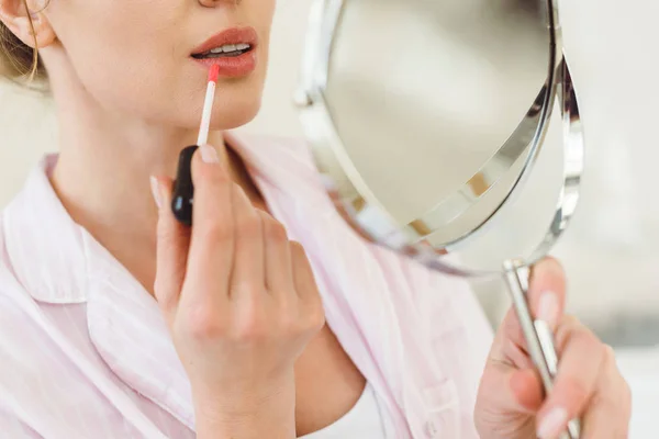 Cropped view of woman looking at mirror and applying lip gloss — Stock Photo