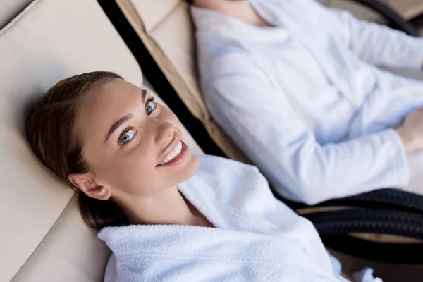 Hermosa mujer joven en albornoz sonriendo a la cámara en el centro de spa - foto de stock