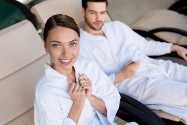 Heureux jeune couple en peignoirs reposant ensemble dans le centre de spa — Photo de stock