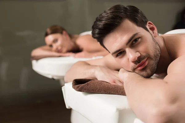 Bella giovane coppia guardando macchina fotografica mentre avendo massaggio nel salone spa — Foto stock