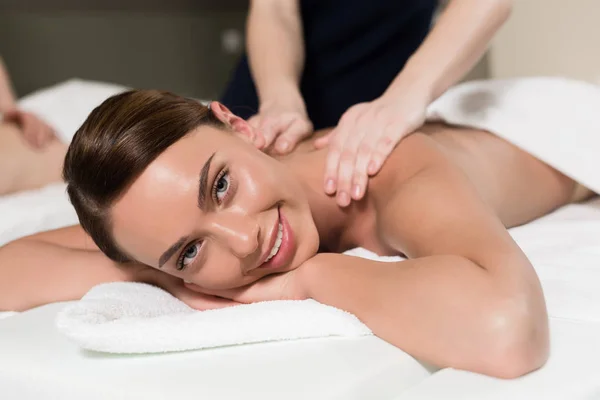Young woman smiling at camera while having body massage — Stock Photo