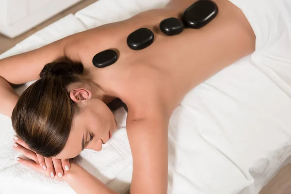 Bela jovem mulher tendo pedras quentes massagem no salão de spa — Fotografia de Stock