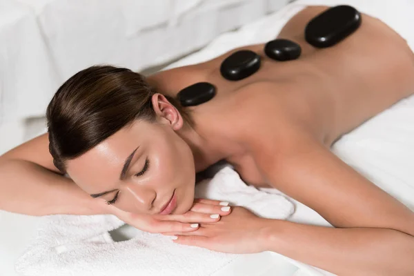 Hermosa joven mujer teniendo piedras calientes masaje en el salón de spa — Stock Photo