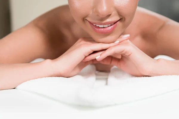 Cropped shot of smiling young woman lying on massage table — Stock Photo