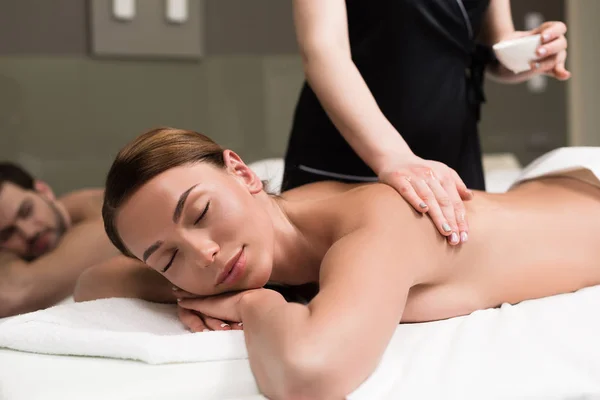 Mujer joven con los ojos cerrados teniendo masaje corporal en el salón de spa - foto de stock