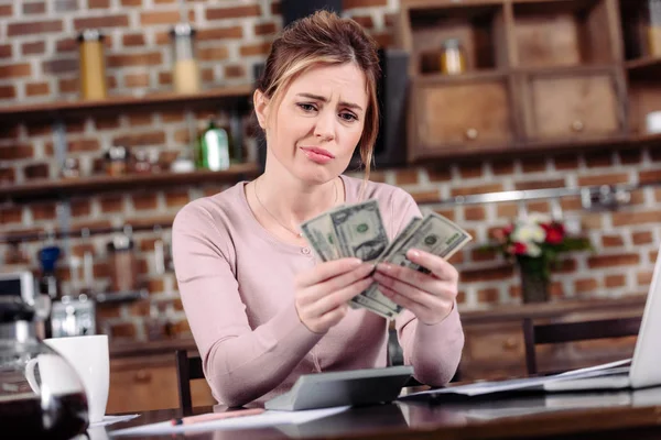 Ritratto di donna sconvolta con guardare i soldi in mano a casa, concetto di problemi finanziari — Foto stock