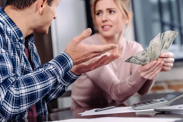 Foco seletivo do casal com dinheiro sentado à mesa em casa, conceito de problemas financeiros — Fotografia de Stock