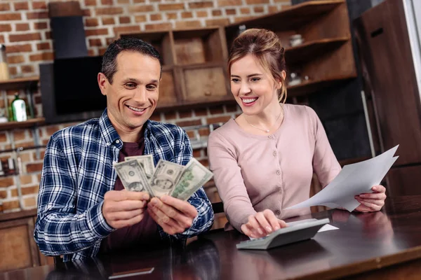 Retrato de pareja feliz contando dinero juntos en casa - foto de stock
