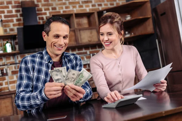 Portrait de couple heureux comptant l'argent ensemble à la maison — Photo de stock