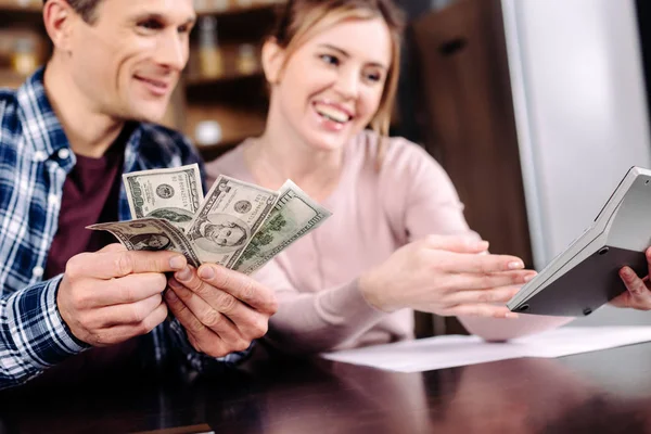 Портрет счастливой пары, пересчитывающей деньги дома — стоковое фото