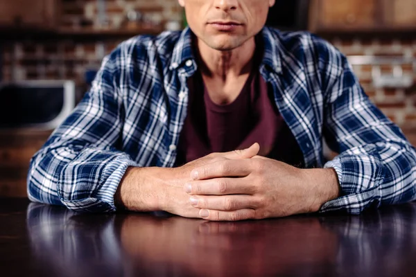 Partial view of man sitting at table in kitchen at home — Stock Photo