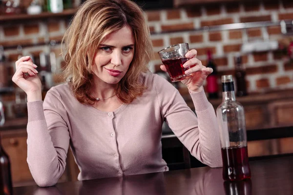 Retrato de mujer con vaso de alcohol mirando a la cámara en casa - foto de stock