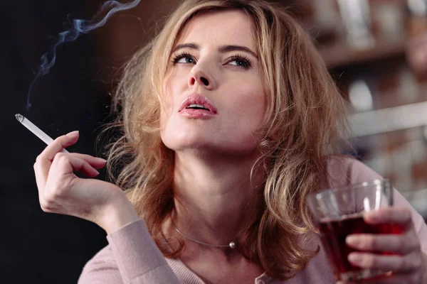 Portrait of pensive woman with glass of alcohol and cigarette — Stock Photo