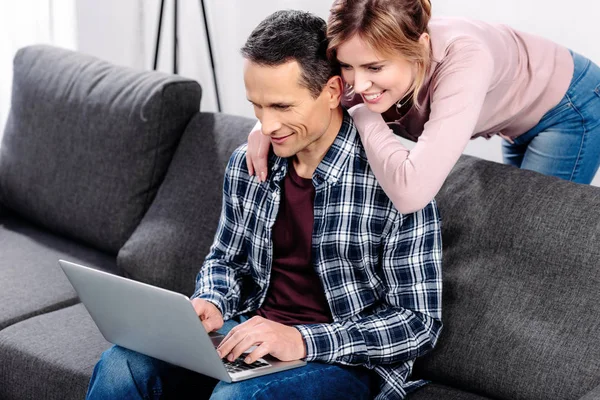 Retrato de casal sorridente com laptop no sofá em casa — Fotografia de Stock