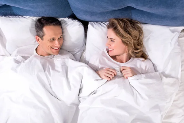 Vue aérienne de la femme et du mari souriants couchés dans le lit à la maison — Photo de stock