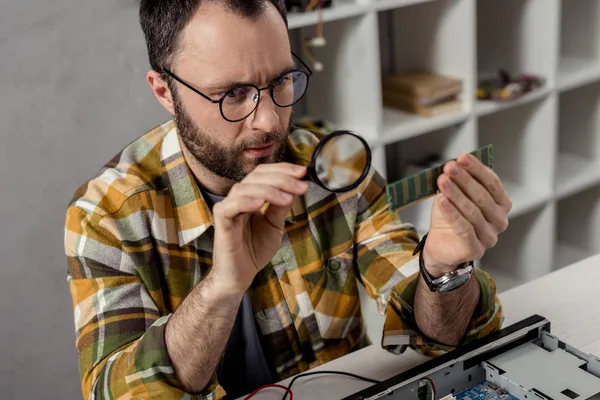 Reparador mirando en ram y usando lupa - foto de stock