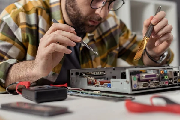 Uomo utilizzando multimetro e frusta durante il fissaggio scheda madre del computer — Foto stock