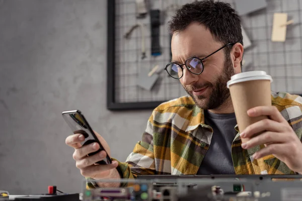 Uomo con caffè in mano utilizzando smartphone su pc rotto — Foto stock