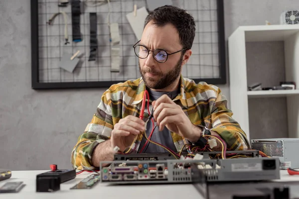 Hombre usando multímetro mientras que fija la PC - foto de stock