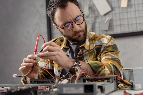 Homme utilisant multimètre tout en fixant pc et détourner les yeux — Photo de stock