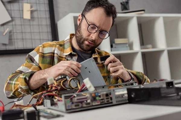 Reparador sentado contra mesa e fixação pc — Fotografia de Stock