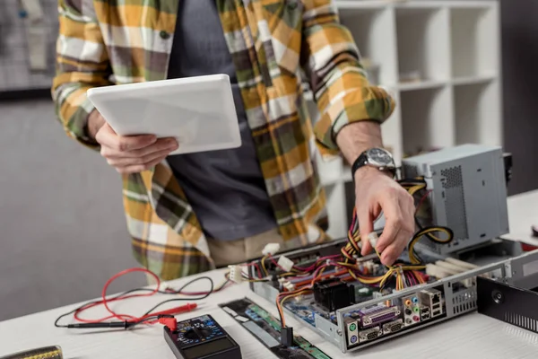 Abgeschnittenes Bild des Menschen mit digitalem Tablet bei der Reparatur des Computers — Stockfoto