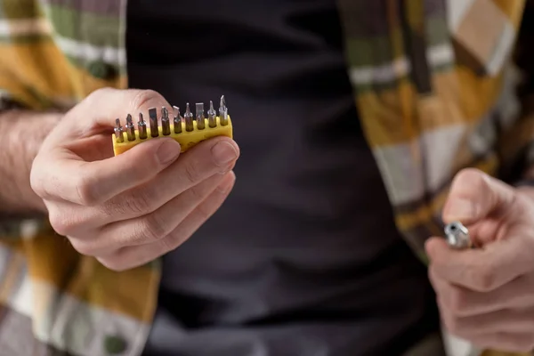 Cropped image of hands holding screwdriver and its attachments — Stock Photo