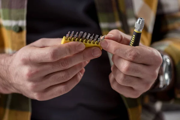 Imagen recortada de las manos que sostienen el destornillador y sus accesorios - foto de stock