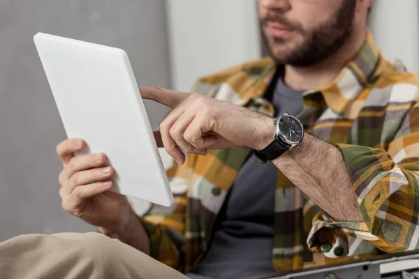 Обрезанное изображение человека с помощью цифрового планшета во время сидения — стоковое фото
