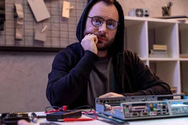 Man in hoodie with hand on chin looking at camera — Stock Photo