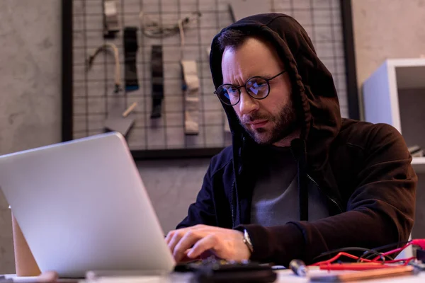 Mann in Kapuzenpullover sitzt und Laptop benutzt — Stockfoto