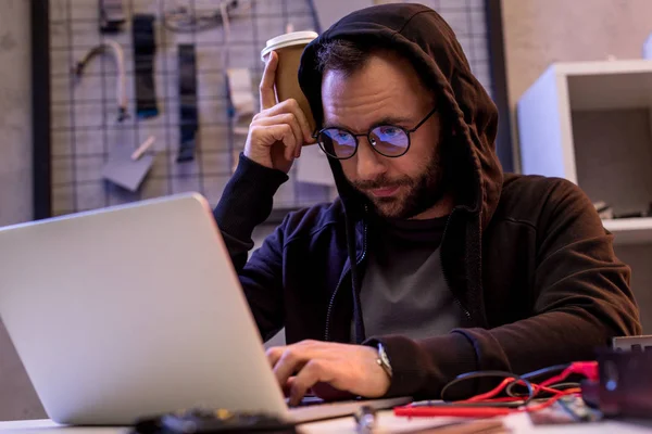 Людина в светрі використовує ноутбук на столі — стокове фото