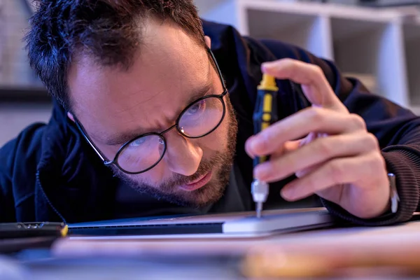 Caucasian man using screwdriver while fixing digital tablet — Stock Photo