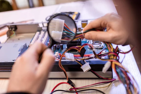 Cropped image image of man using magnifier while looking on wires of pc — Stock Photo