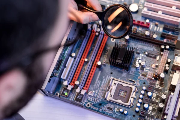 Imagen recortada del hombre usando lupa mientras fija la placa base - foto de stock