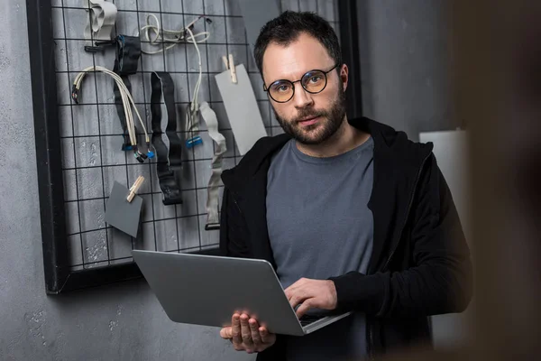 Homem segurando laptop enquanto olha para a câmera — Fotografia de Stock