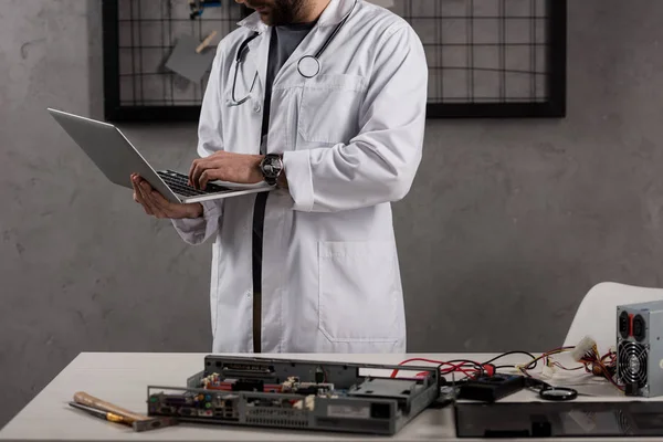 Cropped image of man in white coat and stethoscope over his neck using laptop — Stock Photo