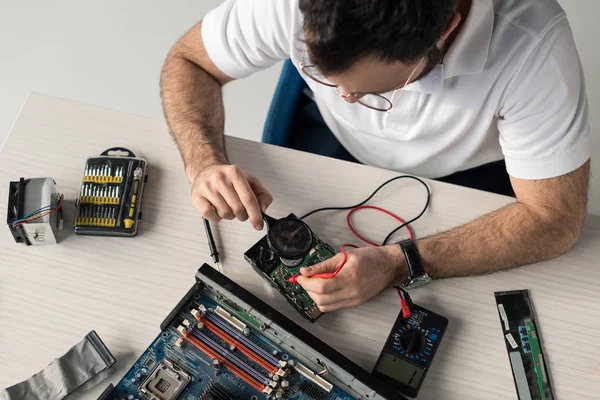 Overhead view of repairman using multimeter while testing hard disk drive — Stock Photo