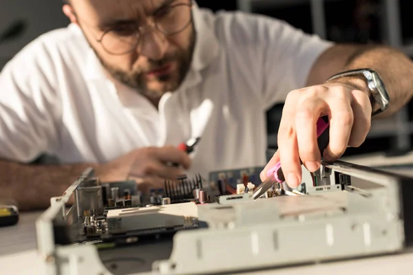 Homem usando pinças enquanto fixa pc quebrado — Fotografia de Stock