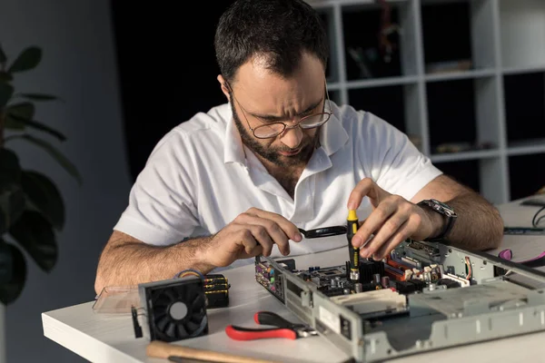 Man using screwdriver while fixing computer motherboard — Stock Photo