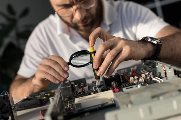 Uomo utilizzando lente di ingrandimento durante il fissaggio pc — Foto stock