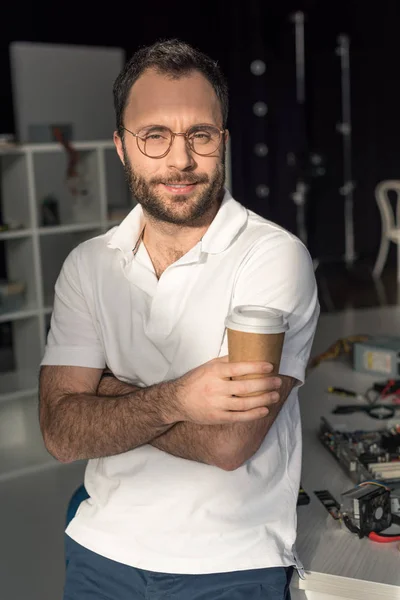 Man with coffee in hand looking at camera while leaning on table — Stock Photo