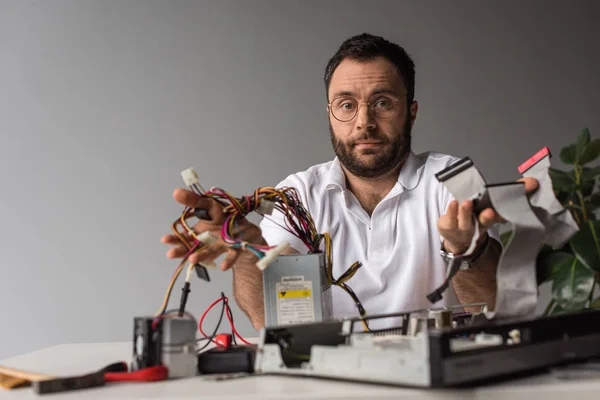 Mann hält Kabel in ausgestreckter Hand über kaputtem PC — Stockfoto