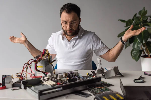 Bewildered man with arms outstretched looking on broken pc — Stock Photo