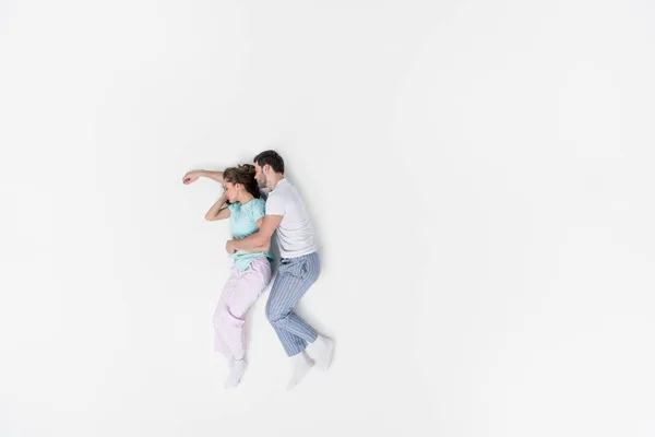 Vista superior de pareja en pijama abrazando y durmiendo juntos aislados en blanco - foto de stock