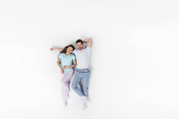 Vue de dessus du couple en pyjama couché ensemble isolé sur blanc — Photo de stock