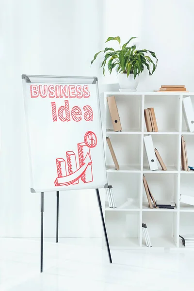 Whiteboard with business idea chart and wooden shelves with folders in office — Stock Photo
