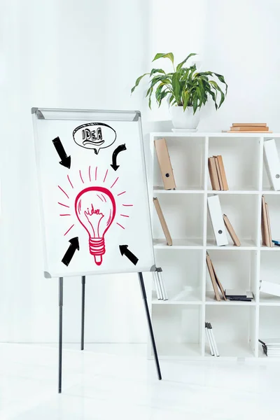 Tableau blanc avec des symboles d'idée et des étagères en bois avec des dossiers au bureau — Photo de stock